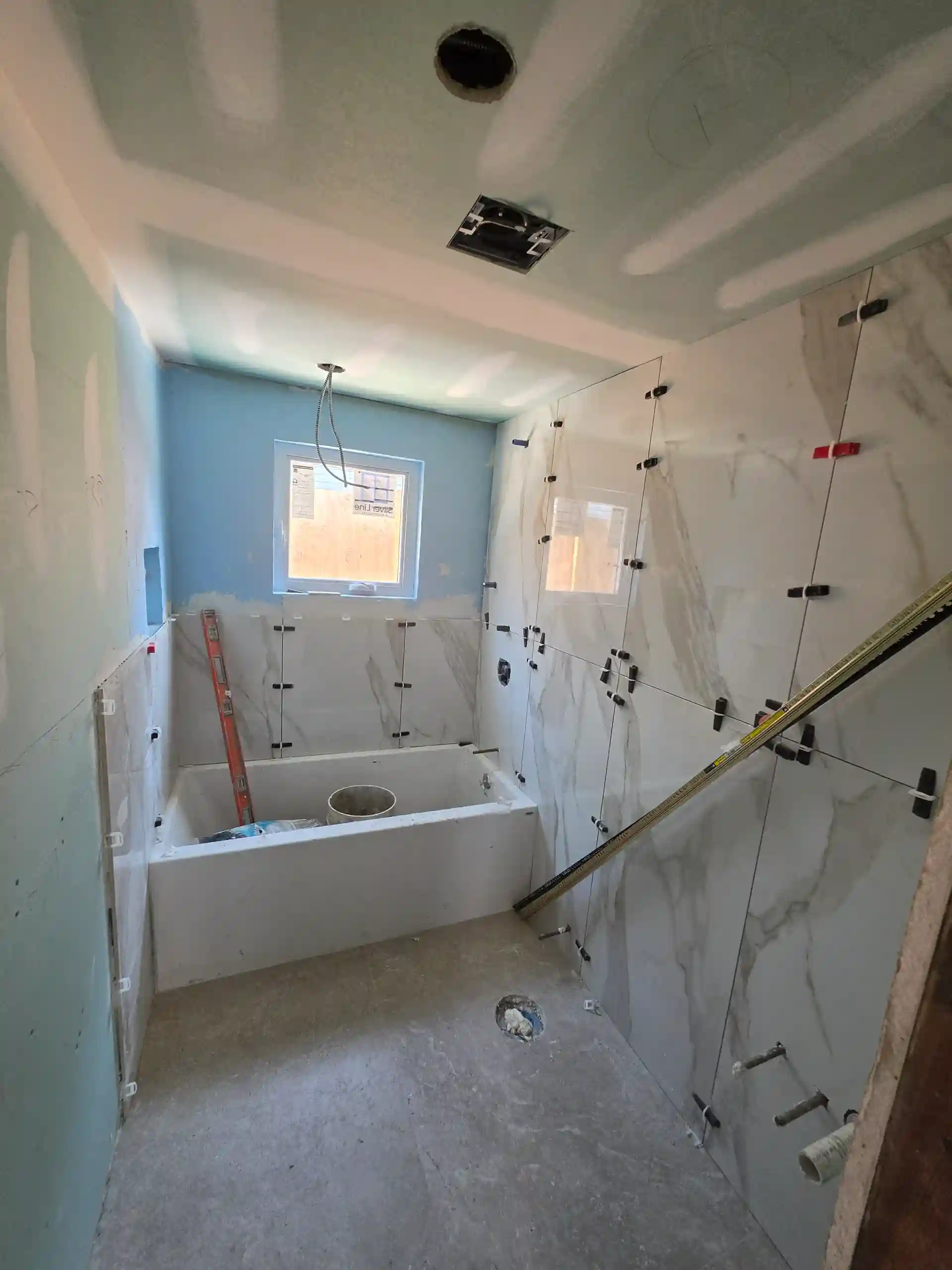 Bathroom renovation in progress with marble tile, bathtub and blue walls by DJ Luxury Renovations Brooklyn