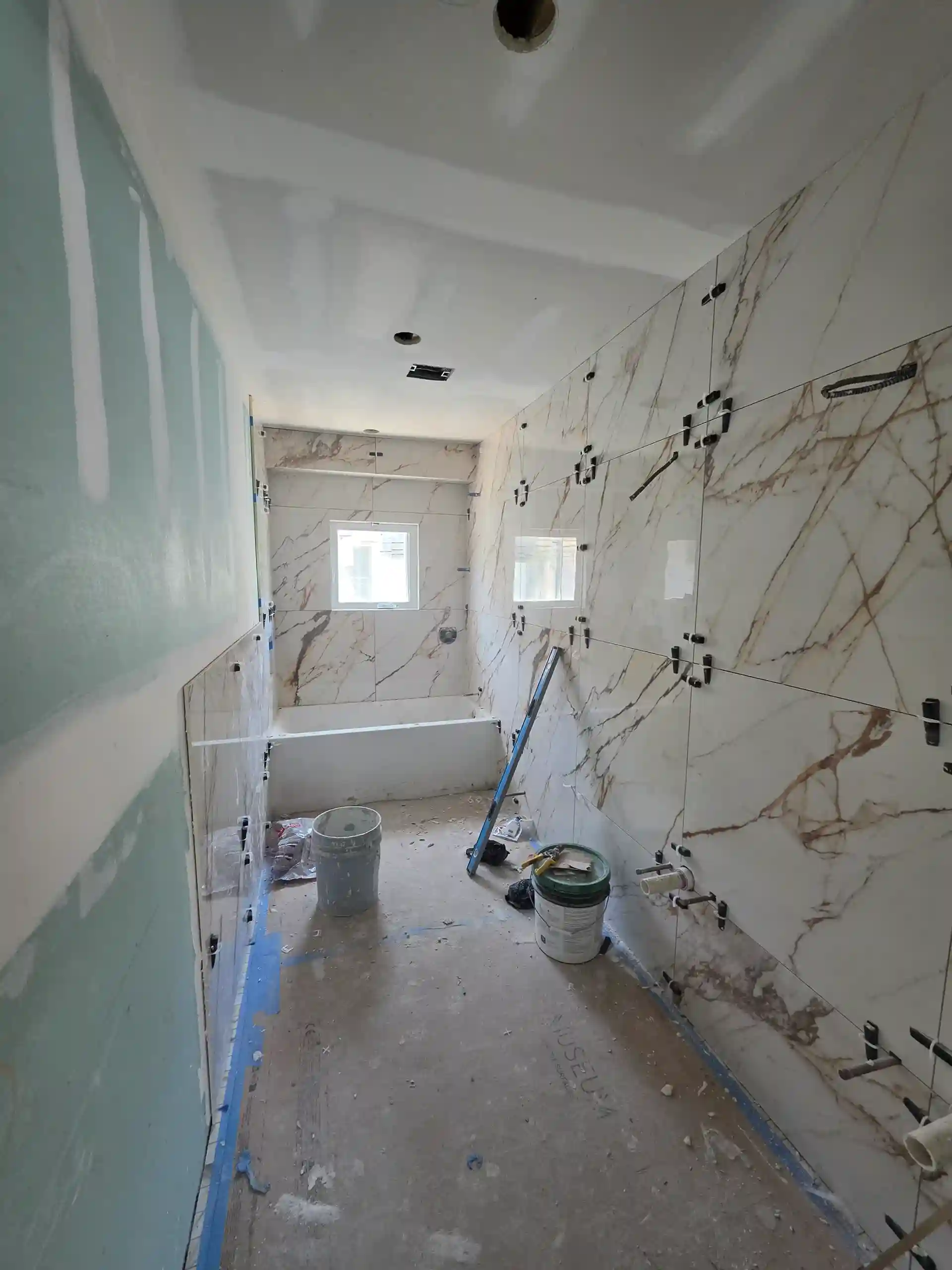 Bathroom renovation in progress with marble-look tile walls and new tub