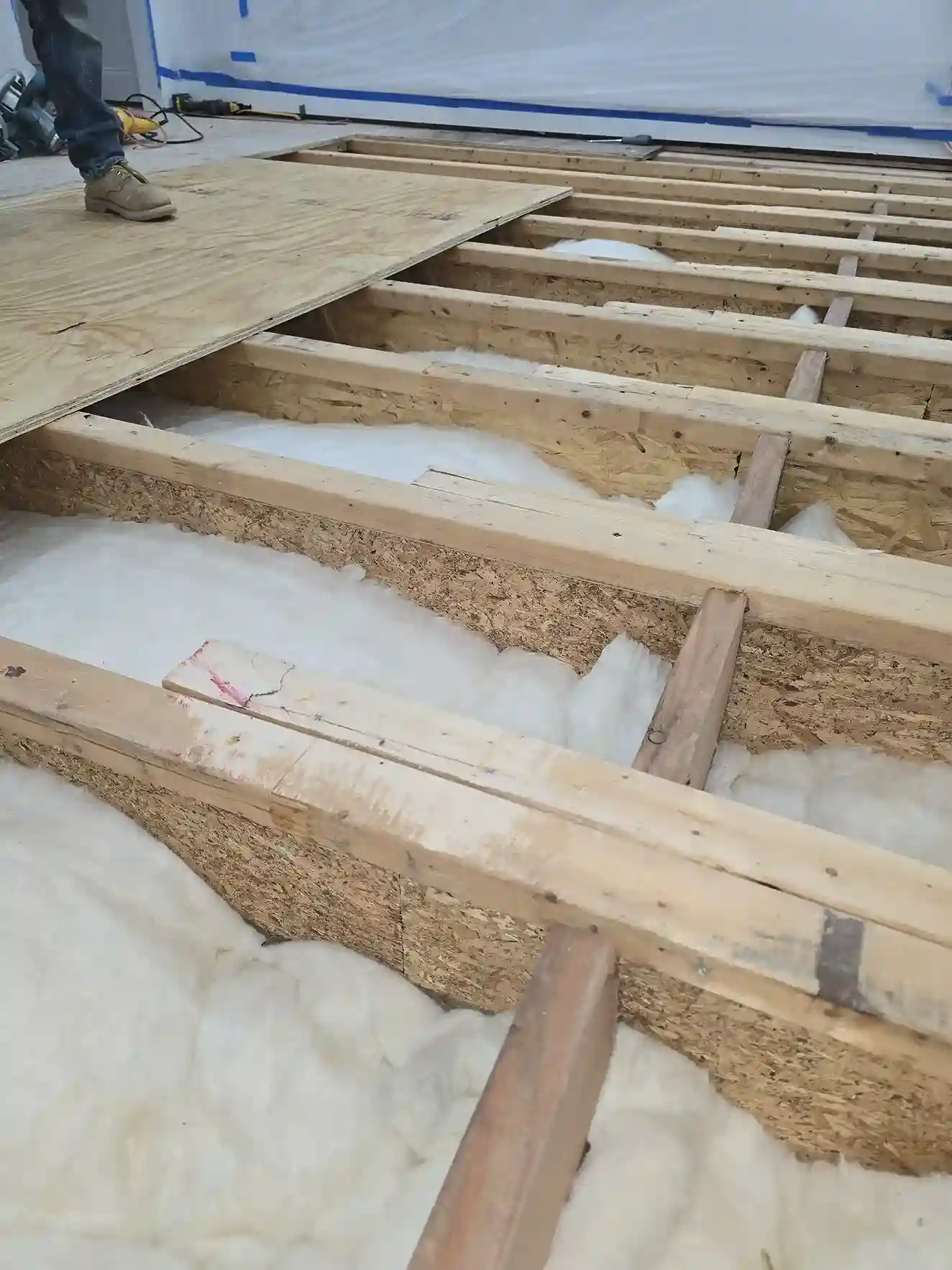 Floor insulation installation between wooden joists during subfloor renovation by DJ Luxury Renovations