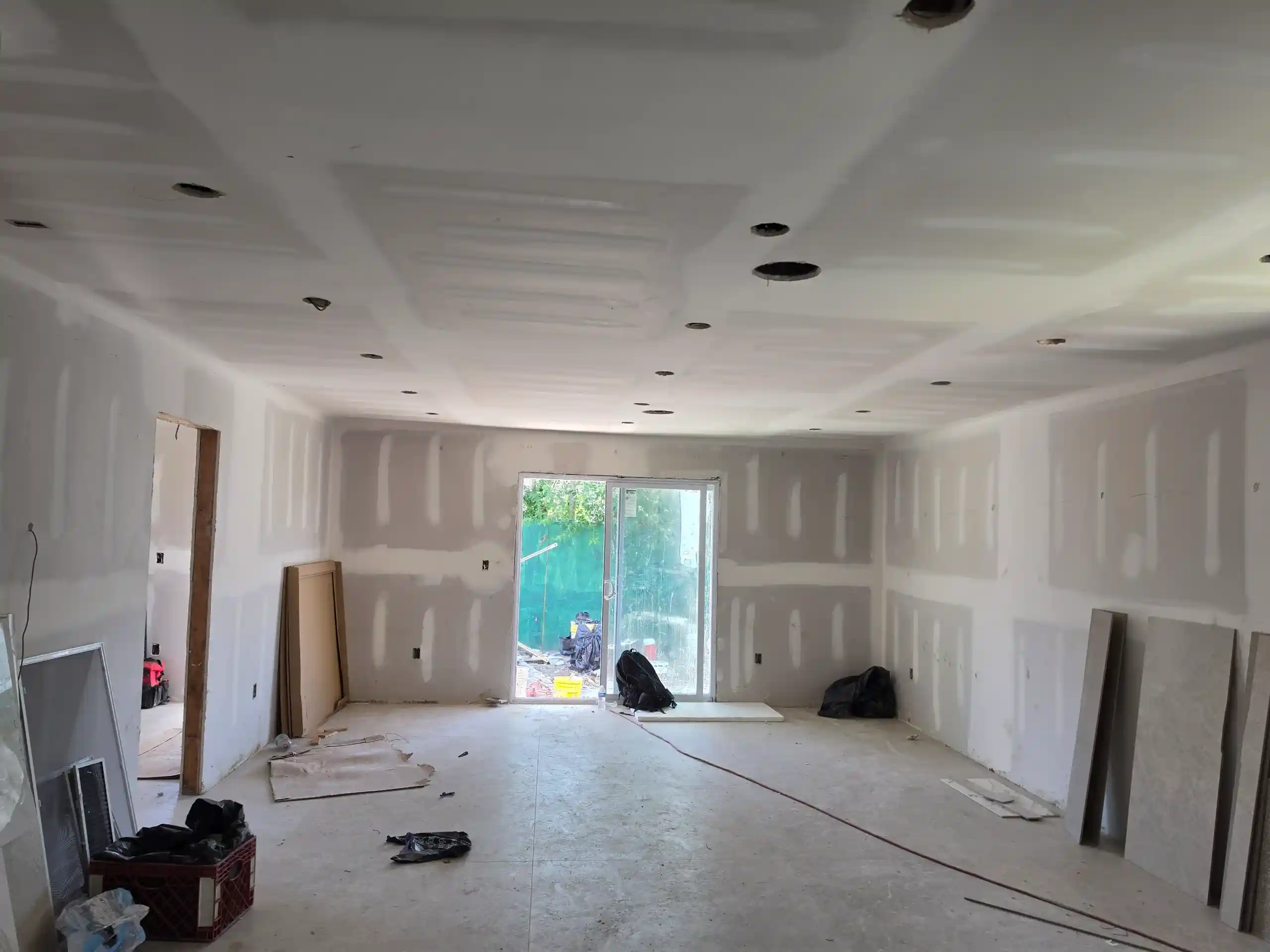 Interior room under renovation with drywall, recessed lighting and sliding glass door in Brooklyn NY