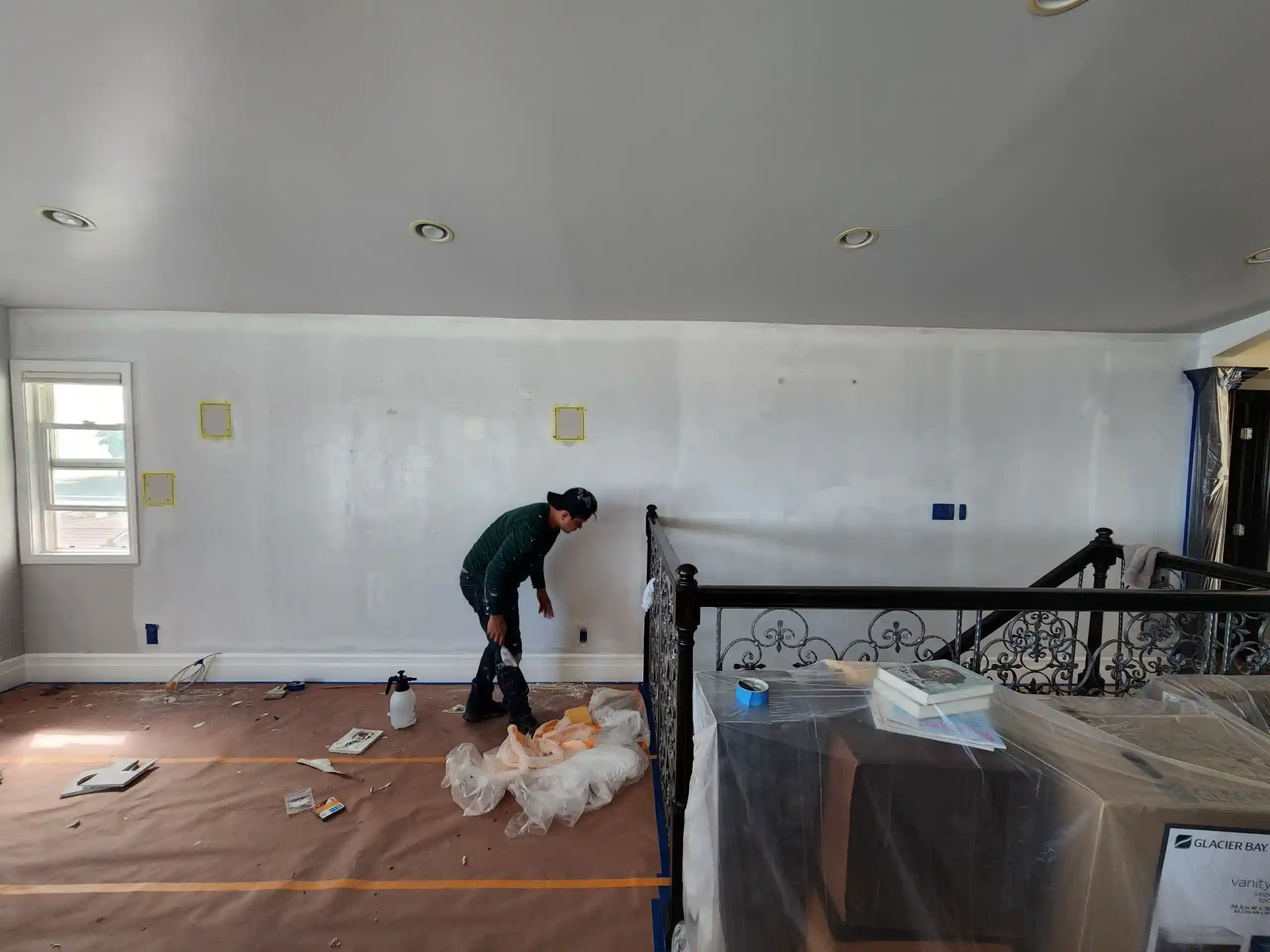 Interior room renovation in progress with worker preparing walls for painting