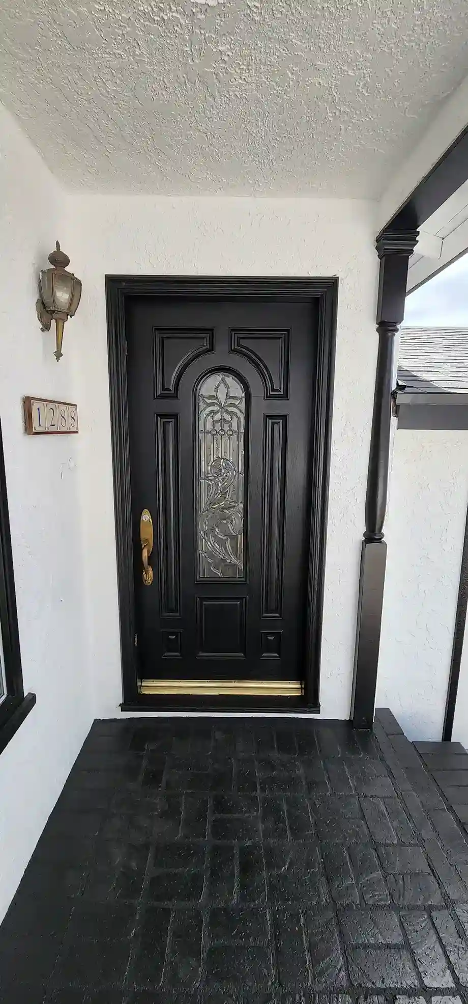 Modern black entry door with glass insert and white stucco exterior renovation in Brooklyn NY