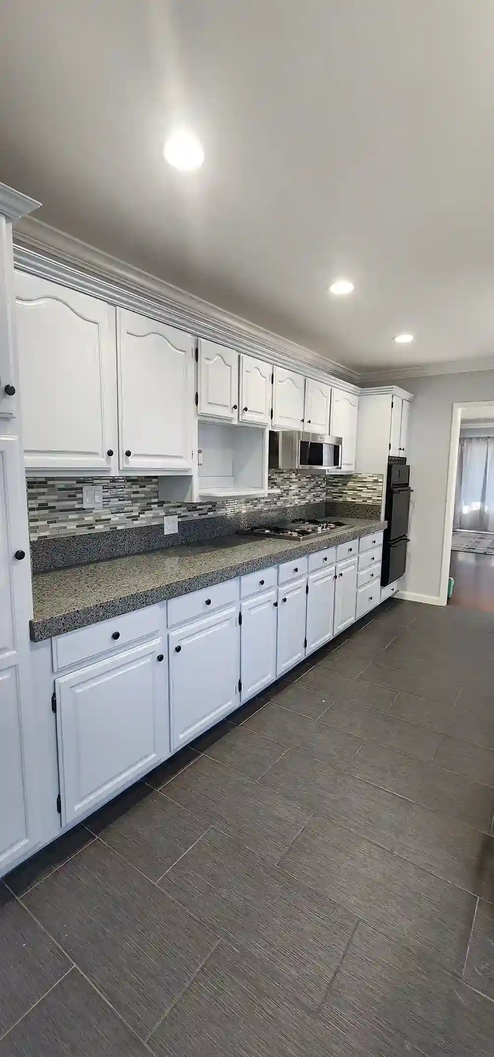 Modern white kitchen renovation with granite countertops, mosaic backsplash and tile flooring in Brooklyn NY
