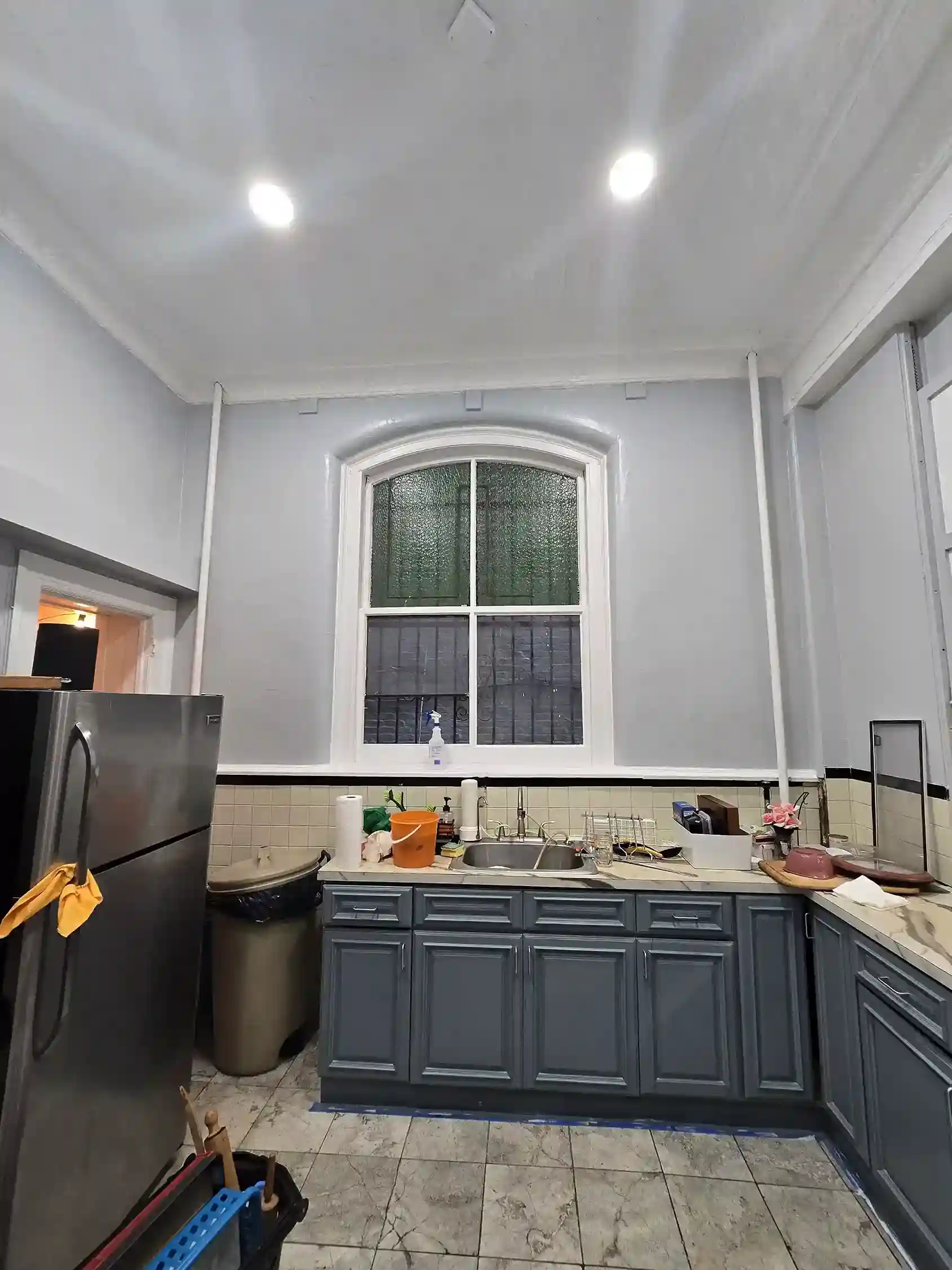 Renovated Brooklyn kitchen with gray cabinets, subway tile backsplash and arched window