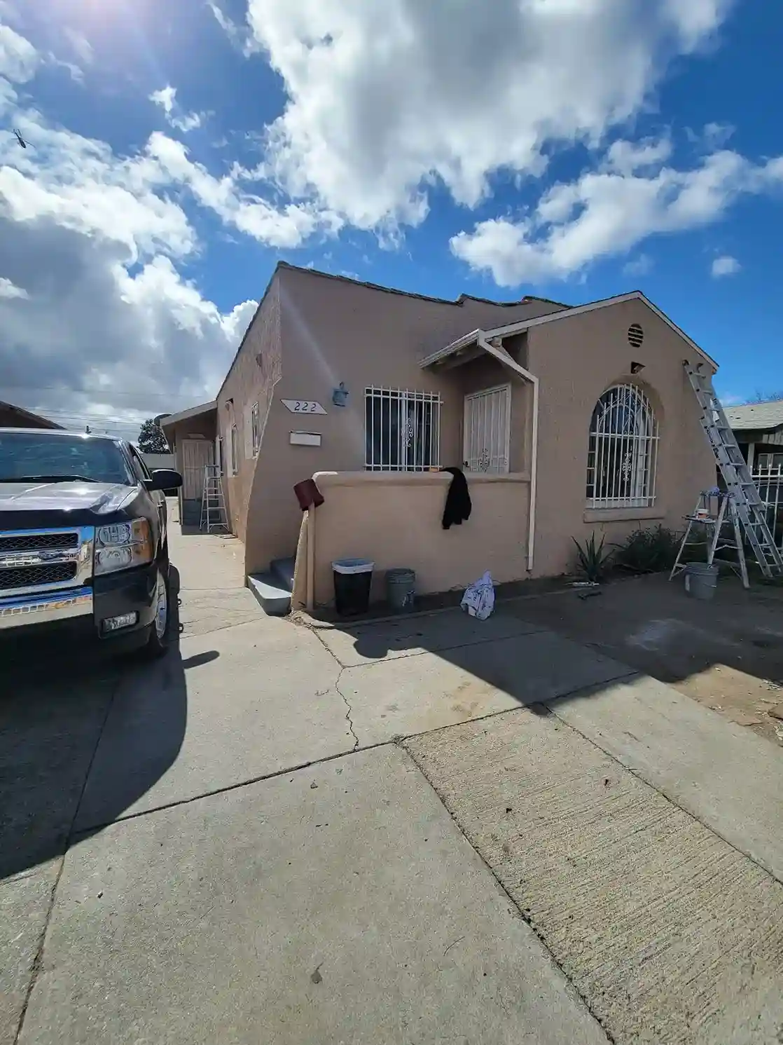 Single-story stucco home exterior with arched window before renovation in Brooklyn NY